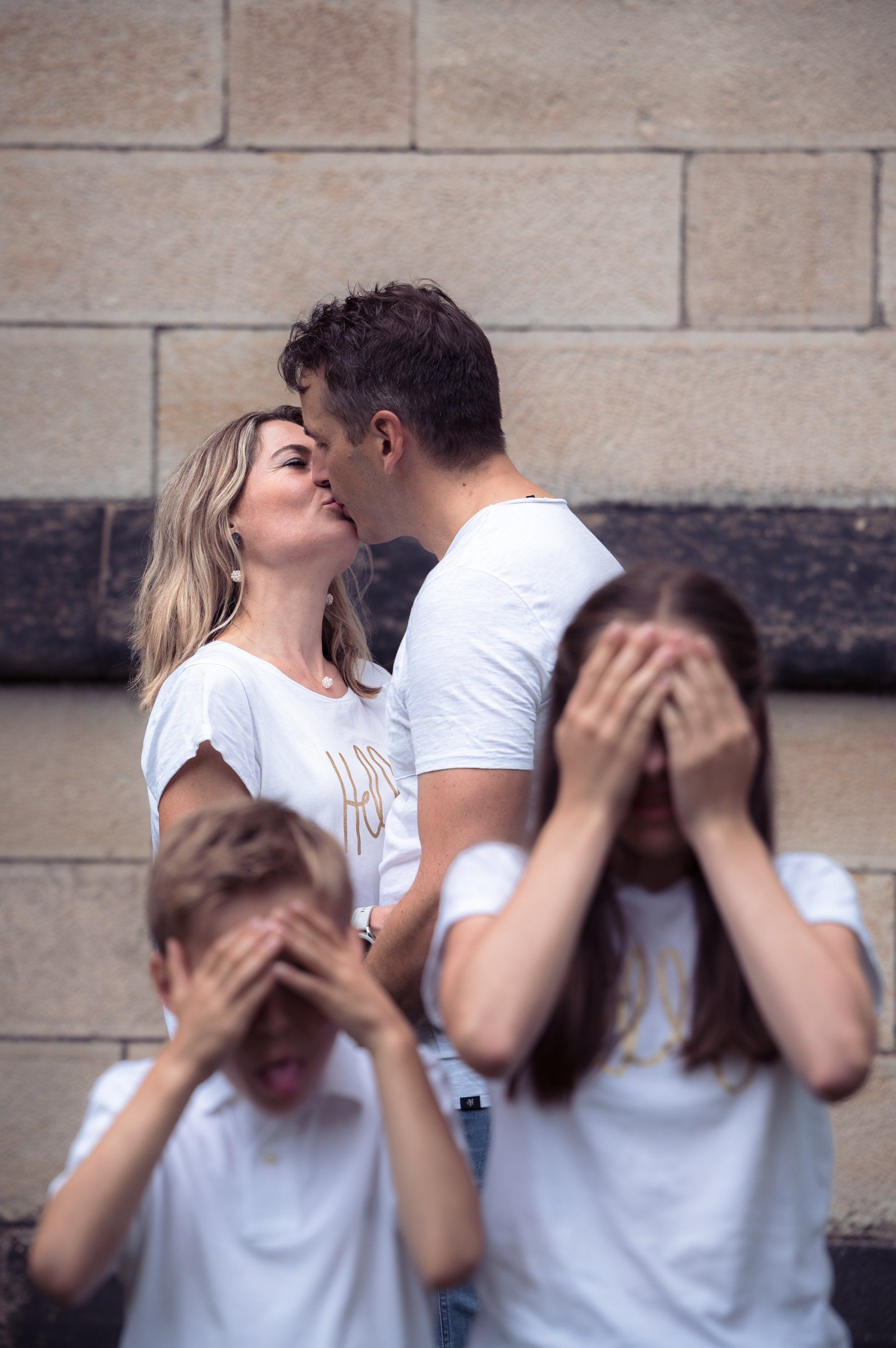 Eltern küssen sich, die Kinder halten sich die Augen zu