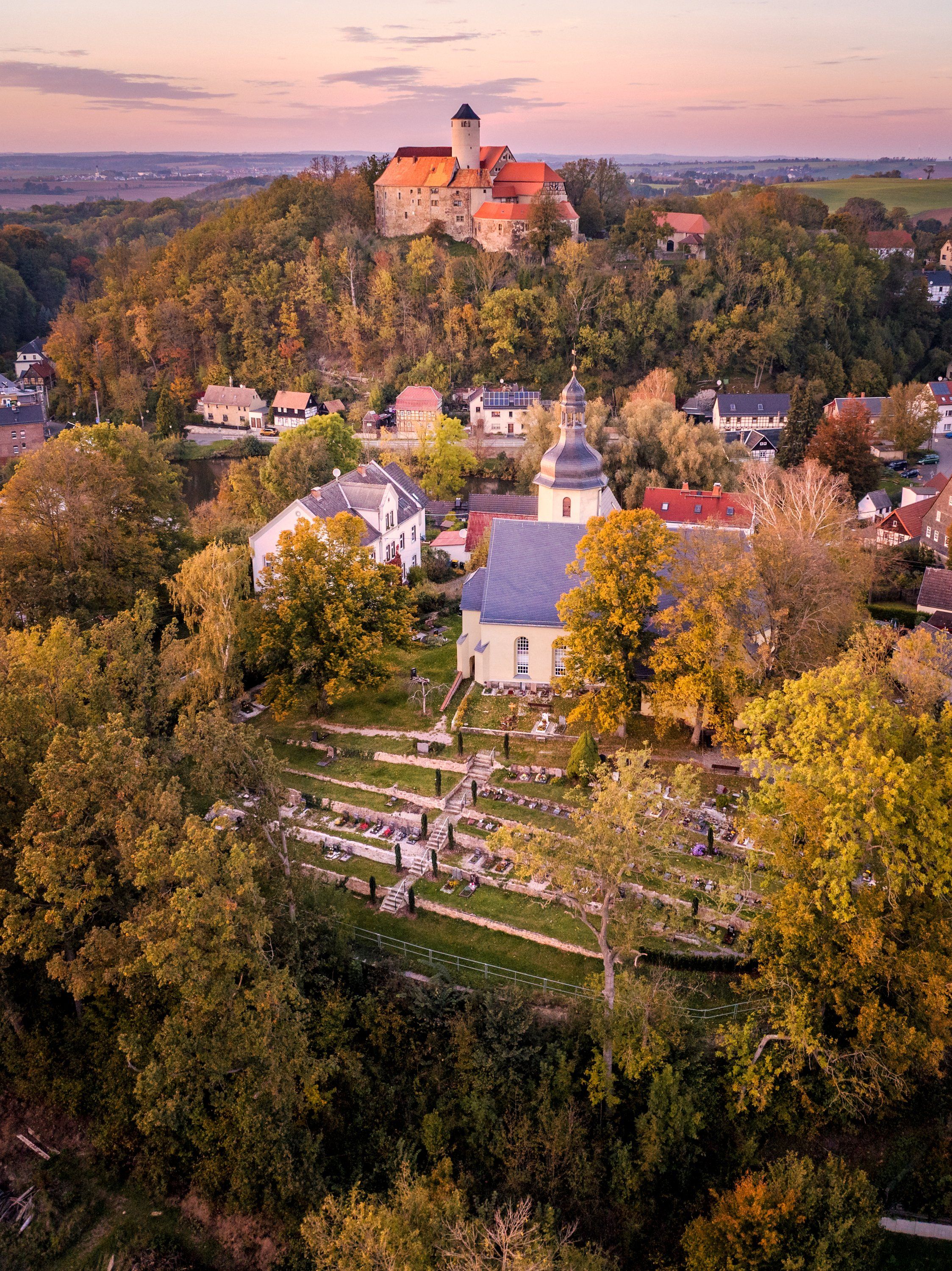 Ort mit Burg und Kirche im Abendlicht, Luftaufnahme