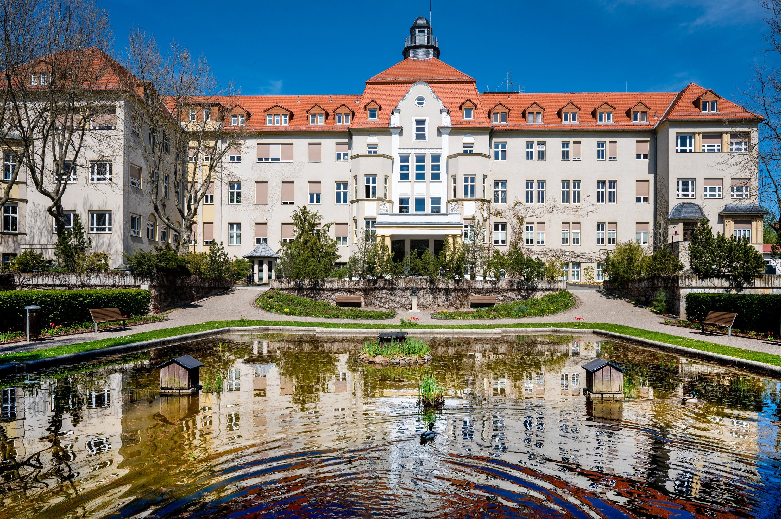 Historisches Klinikgebäude spiegelt sich im Teich