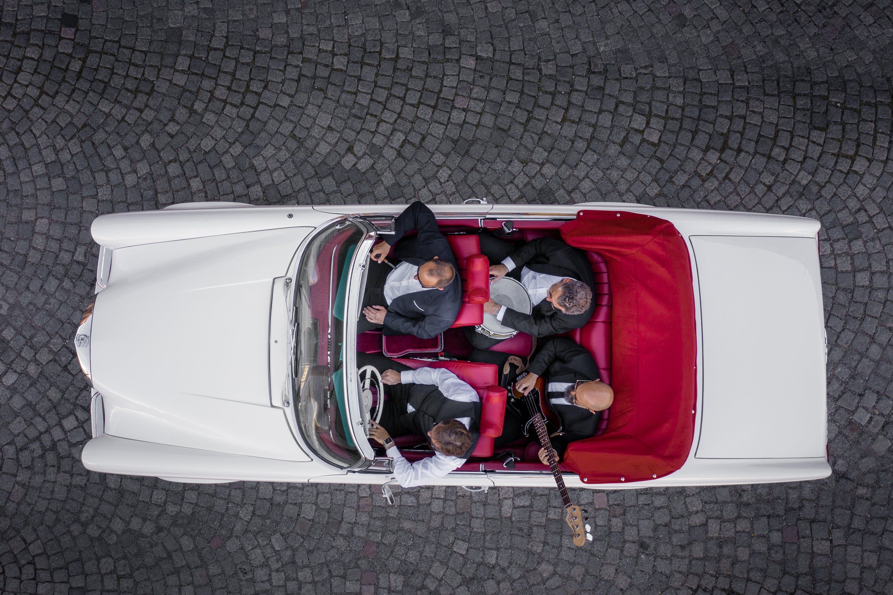 Weißes Cabrio mit Band von oben fotografiert