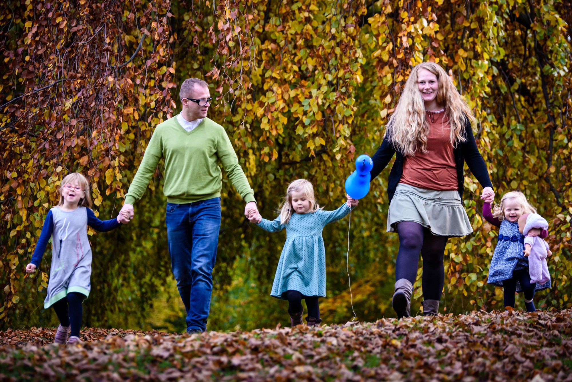 Familie spaziert lachend durch Herbstlaub